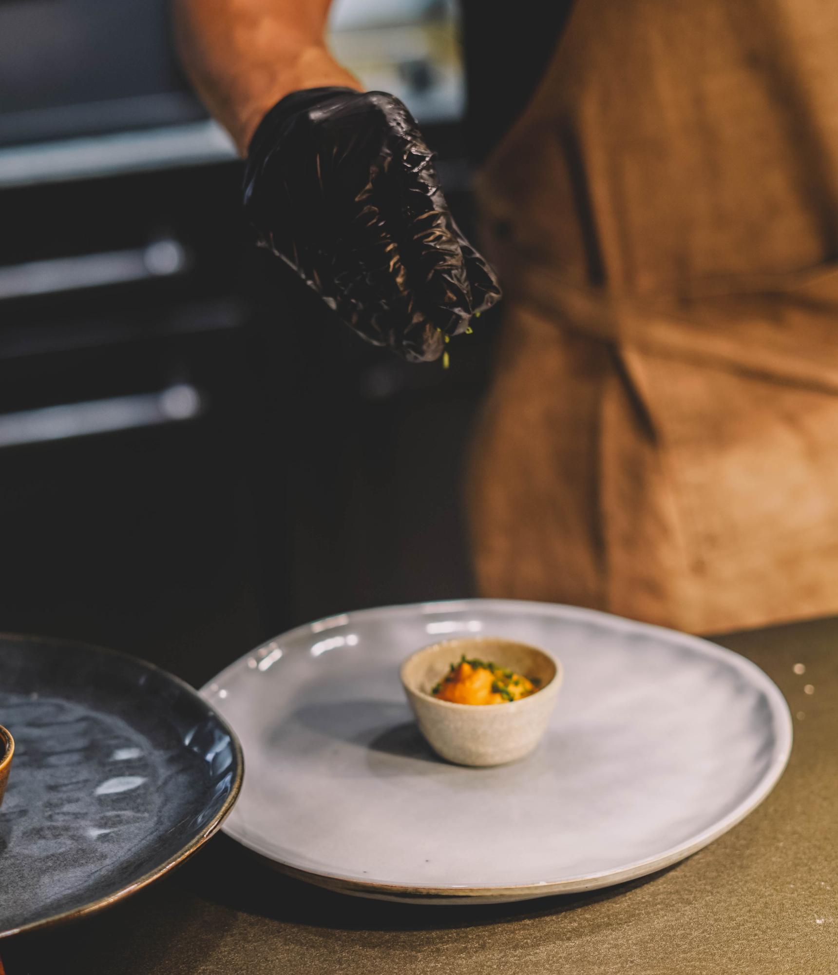 Chef plating a composed dish on a dark table